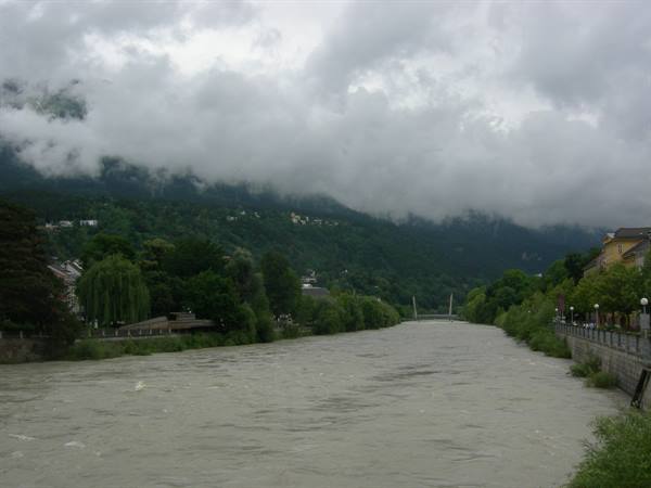 The Inn river with a bridge in Innsbruck, mountains under low clouds