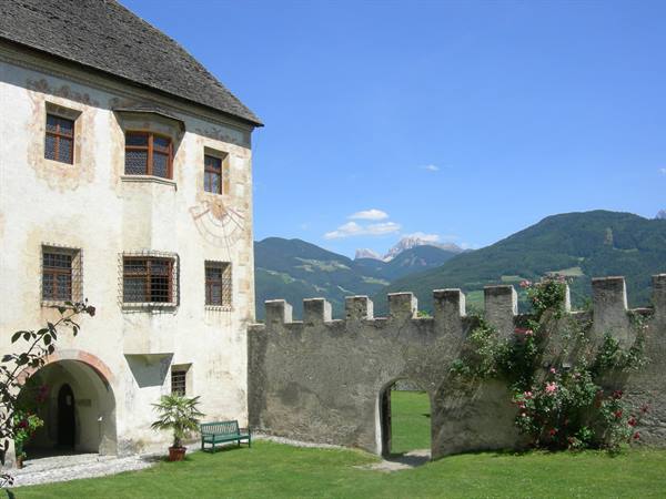 Castle battlements with climbing roses, frescoed walls and Dolomites peaks behind