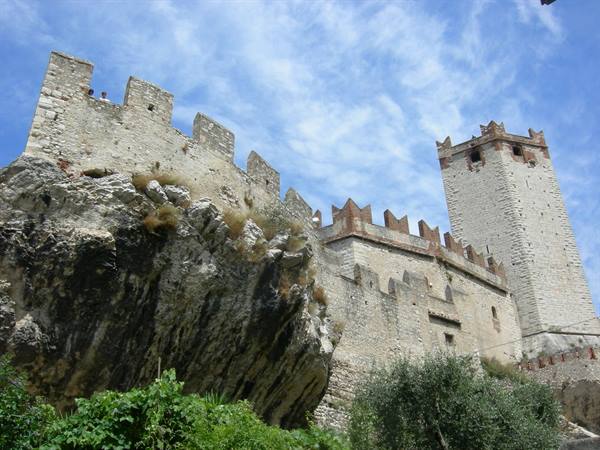 Malcesine Castle, stone walls and tower on rock, blue sky with clouds