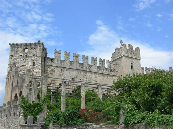 Crenellated walls of Malcesine's Scaligero castle above the green pergola