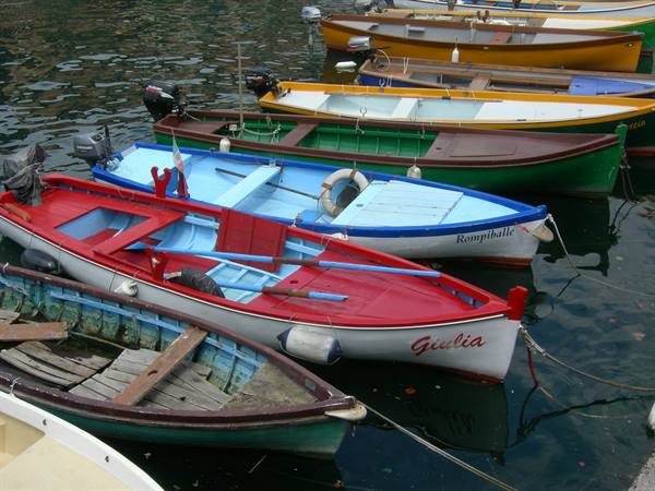 Colorful wooden fishing boats, one red named Giulia, moored at the harbor