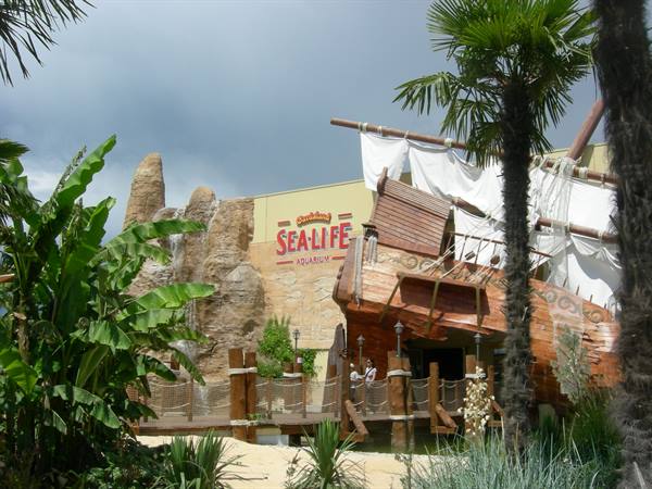 Entrance of Gardaland Sea Life aquarium with wooden pirate ship and palm trees