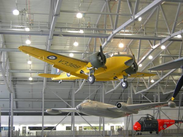 Historic aircraft suspended among steel trusses in a lit aviation museum