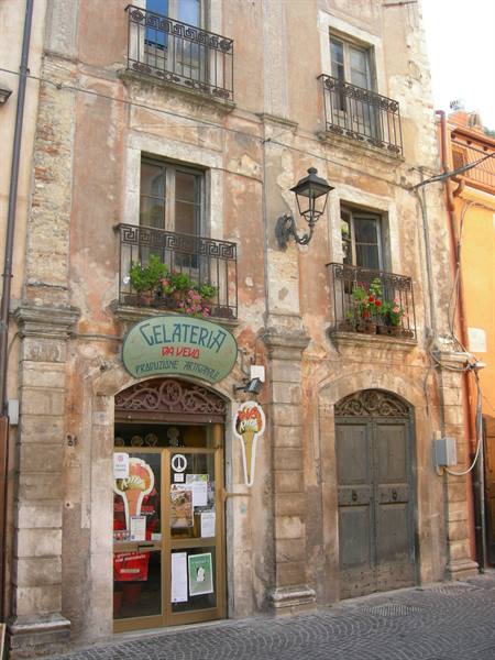 Old Da Vela gelateria on weathered stone facade with flowered balconies