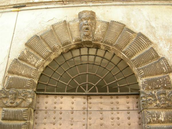 Stone portal with rusticated arch and carved grotesque masks