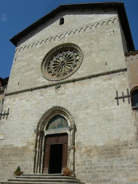 Medieval stone church facade with carved rose window and pointed portal