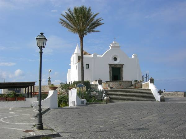 White Santa Maria del Soccorso church in Forio, palm tree and steps by the sea