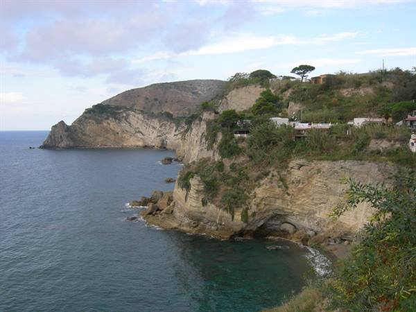 Green tufa cliffs over blue sea, houses among pines on Ischia