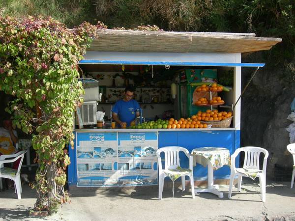 Juice stand with oranges and lemons, white tables, vendor at work