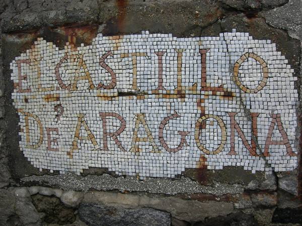 Tesserae mosaic reading El Castillo de Aragón on a rough stone wall