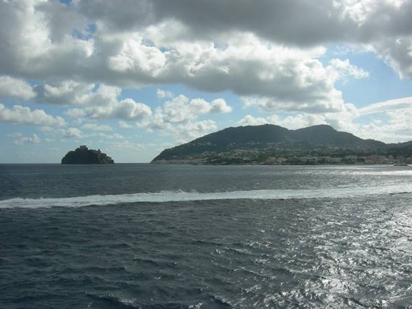Aragonese Castle on volcanic rock islet, choppy sea and clouds over Ischia