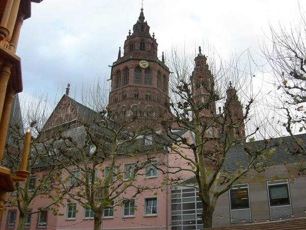 Mainz Cathedral's red stone towers rise behind pink houses and bare trees