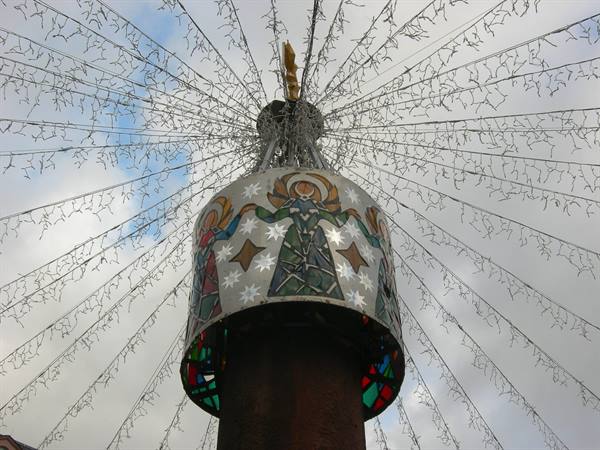 Christmas structure decorated with angels, radiating light strings against cloudy sky