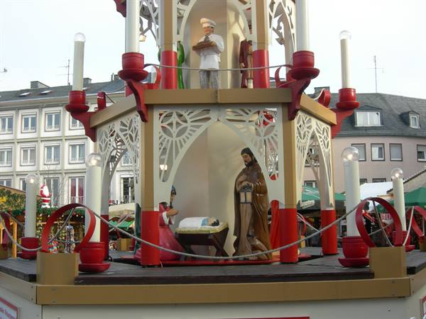 Wooden Christmas pyramid with nativity figures and candles at a market