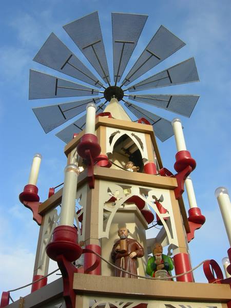 Wooden Christmas pyramid with painted figurines, red candles and metal sails