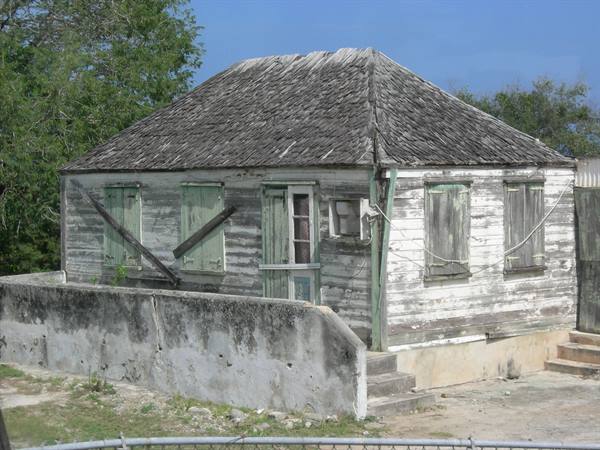 Old weathered wooden house with shingle roof and closed green shutters