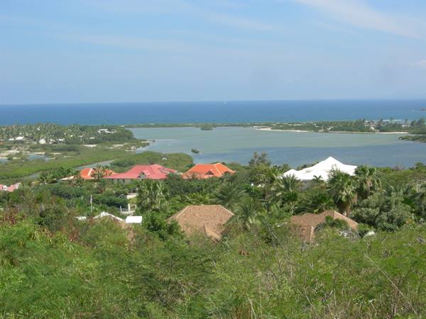 Red-roofed villas among palms by a turquoise lagoon, blue ocean beyond