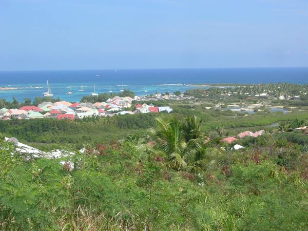 Marigot's colorful rooftops among palms, sailboats anchored in turquoise sea