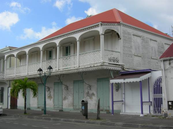 White wooden creole house with arched balcony and red roof
