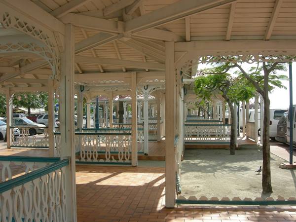 White wooden pavilion with pierced railings, sunlight and trees