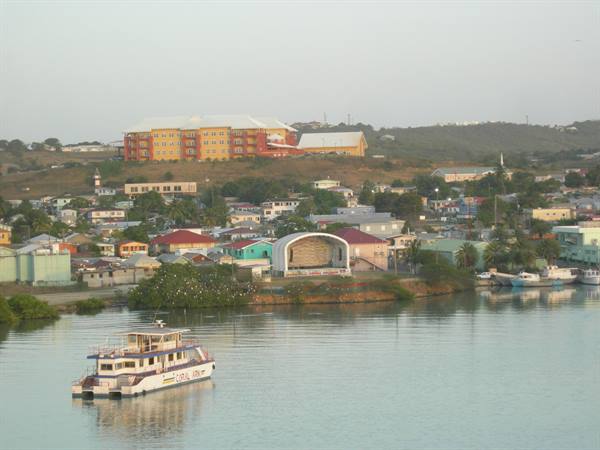 White ferry moored in St. John's harbor, Antigua, colorful hillside buildings