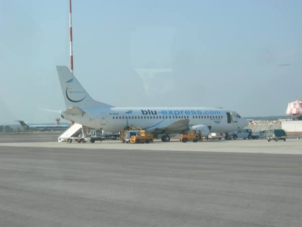 Blu express airplane parked on the tarmac with service vehicles under blue sky