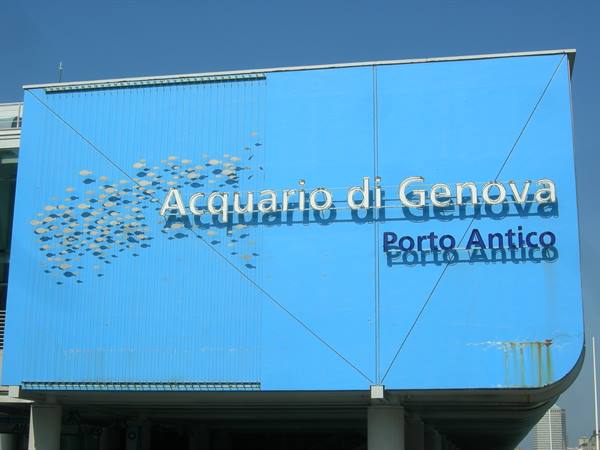 Blue sign of the Acquario di Genova at Porto Antico, silver letters under clear sky