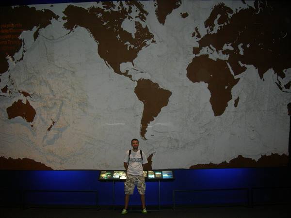 Tourist in white t-shirt posing in front of a large world map wall