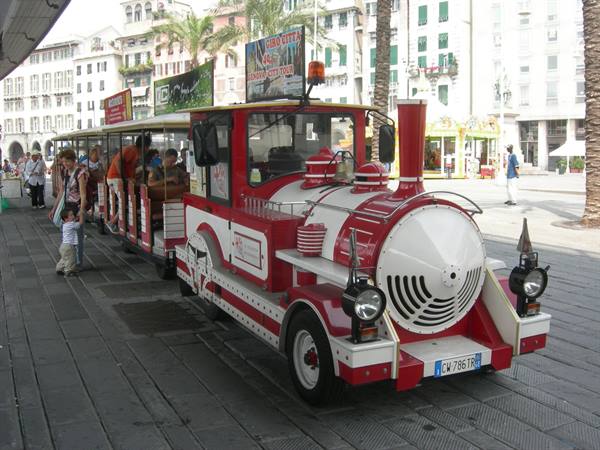 Red and white tourist trackless train on a plaza, passengers boarding