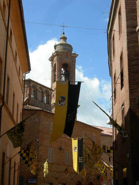 Yellow and black flags between brick buildings, brick bell tower in background