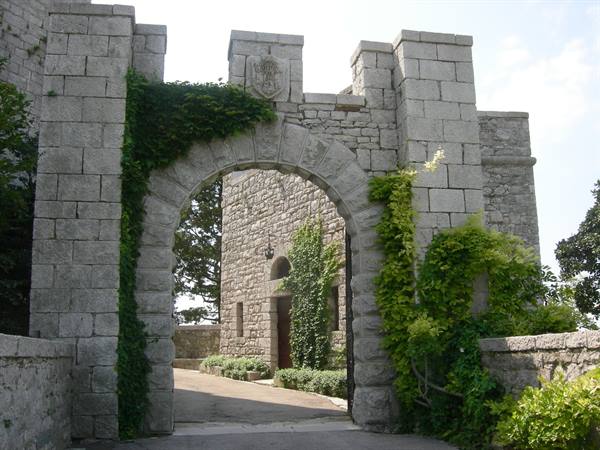 Grey stone arched gate with carved coat of arms, climbing ivy, inner courtyard