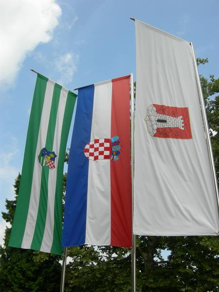Zagreb and Croatian flags waving on tall poles against blue sky