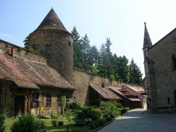 stone tower with conical roof, walls, red-tiled roofs and cobbled lane