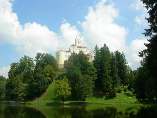 White Trakošćan castle on wooded hill reflected in lake