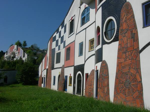 Curved Hundertwasser building facade with ceramic mosaics and colorful windows