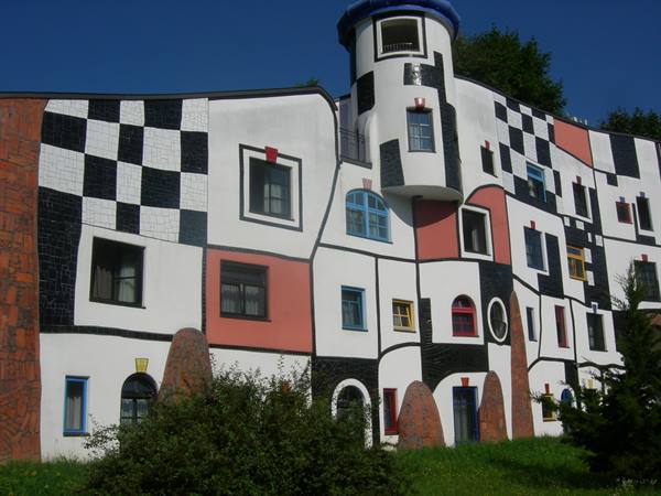 Hundertwasser-style colorful building with black-and-white checkerboard and round tower