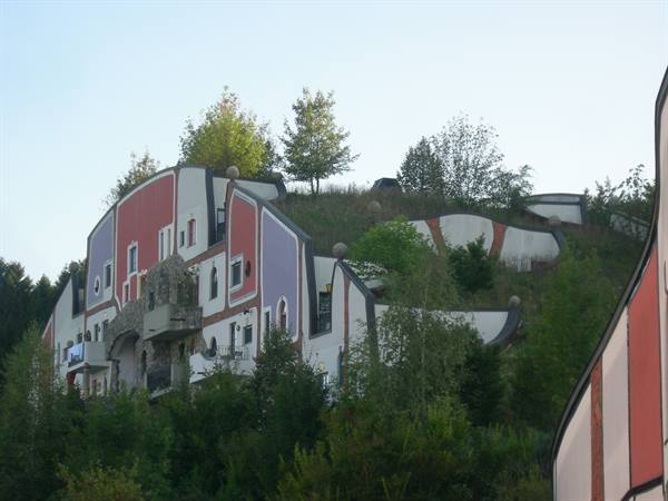Hundertwasser building with colorful facades and trees on grassy roof