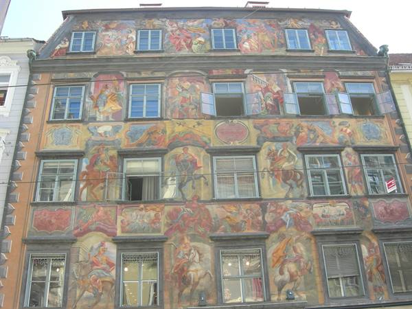 Painted facade in Graz, windows open among baroque frescoes