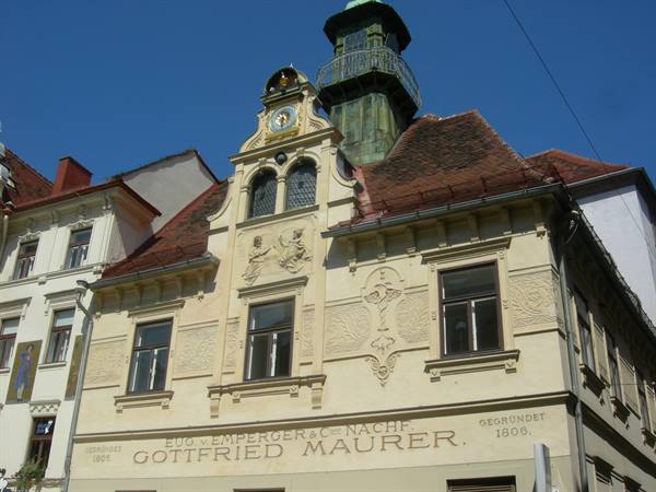 Historic Gottfried Maurer building with golden clock and green copper tower in Graz