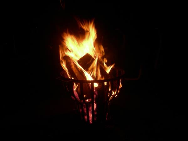 Fire burning in a metal fire basket, orange flames against the dark night