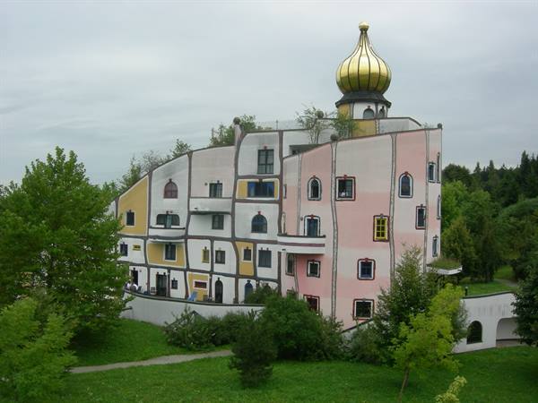 Whimsical colorful building with golden dome among green trees, soft light