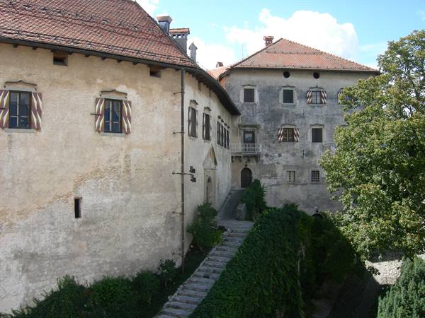 Old buildings with tiled roofs and shutters, stone staircase between greenery