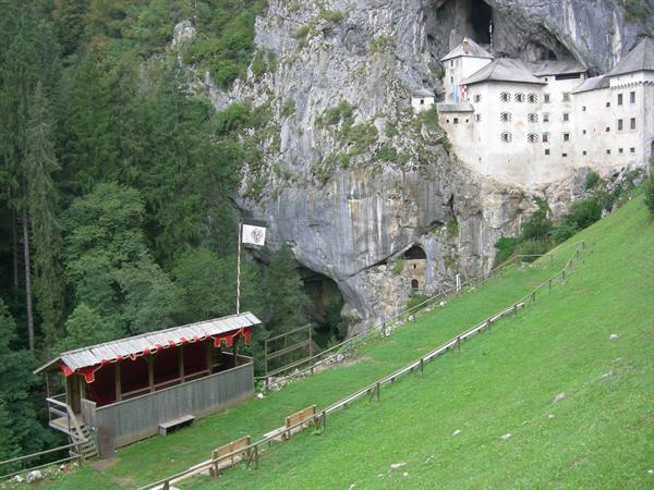 Predjama Castle built into the cliff, wooden stand on the green meadow