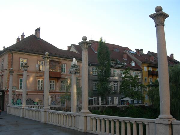 Stone columns on bridge balustrade, old houses in Ljubljana