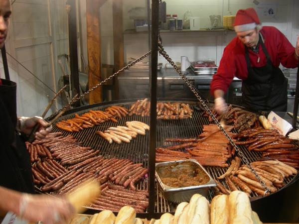 Cook in Santa hat grilling sausages on the huge circular grill