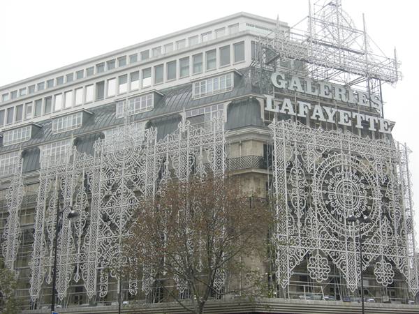 Galeries Lafayette wrapped in white decorative scaffolding mesh, overcast sky