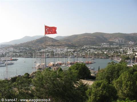 Turkish flag waving over Bodrum harbor full of boats