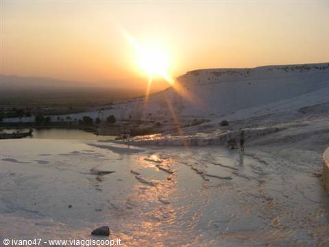 Tourists on Pamukkale's white travertine terraces under the low sun
