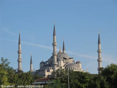 The Blue Mosque in Istanbul rises among trees under a blue sky