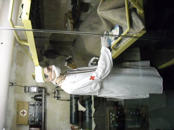 Mannequin of a Red Cross medic among oxygen tanks in a museum bunker infirmary
